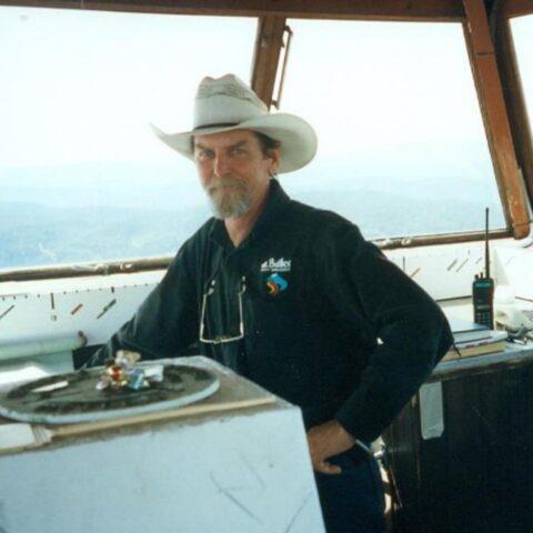 Chris Deutschere in white hat with windows behind showing smoke and mountains