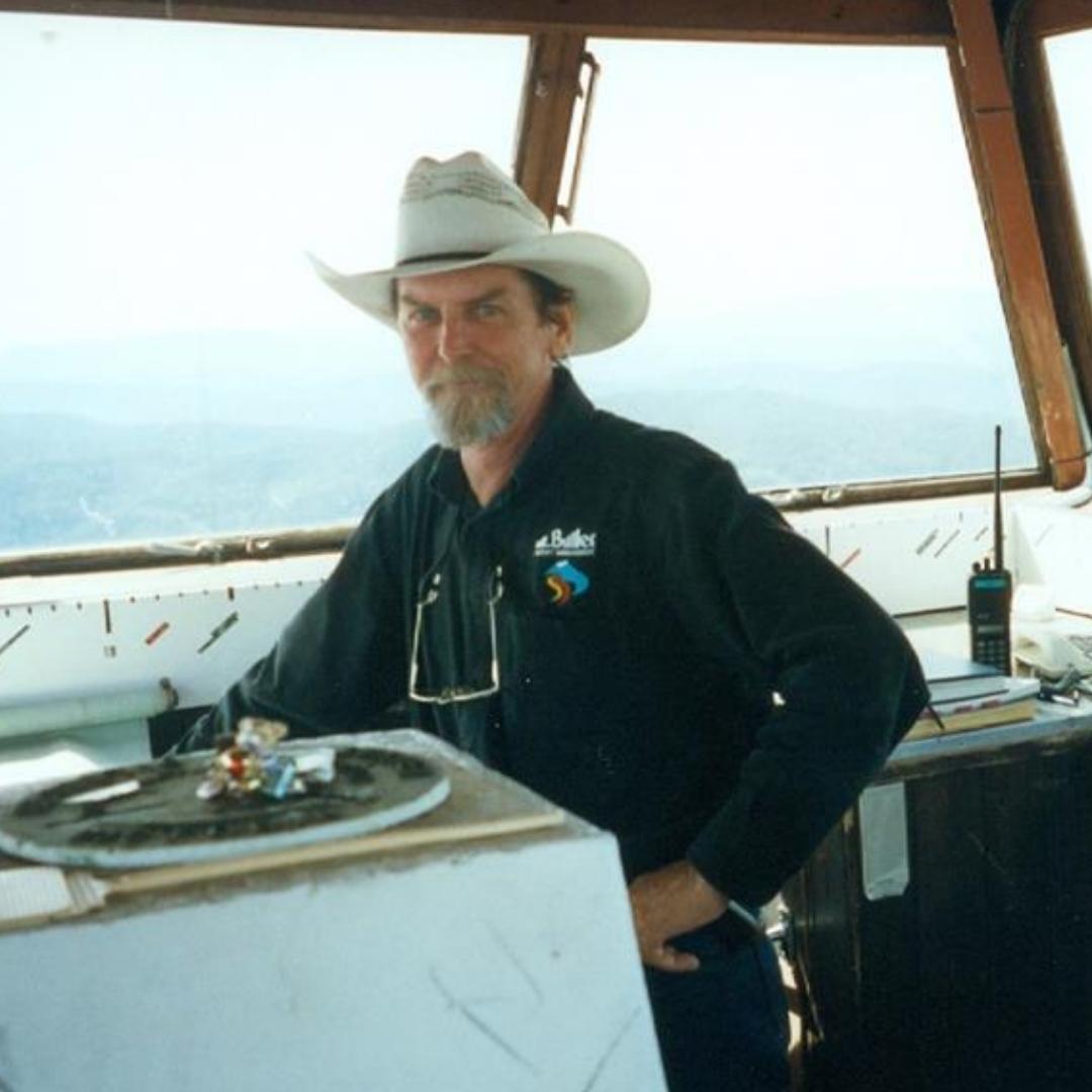 Chris Deutschere in white hat with windows behind showing smoke and mountains
