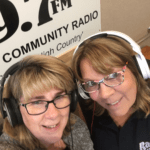 two women looking up into the camera as they take a selfie in the studio with the Radio Mansfield sign behind them